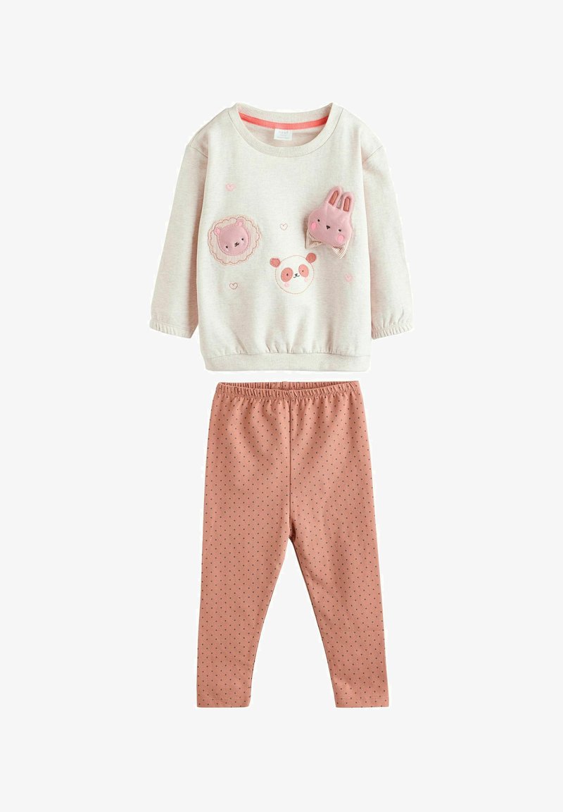 Vaaleanbeige huppari, jossa on eläinkuositteet, yhdistettynä vaaleanpunaisiin legginsseihin, joissa on pieniä laivastonsinisiä pilkkuja ja joustava vyötärö.