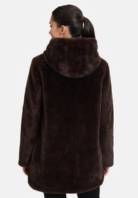 Bruine faux fur jas met een grote capuchon, ontworpen met een ontspannen fit en een gladde textuur. Naadloze achterkant en lange mouwen.