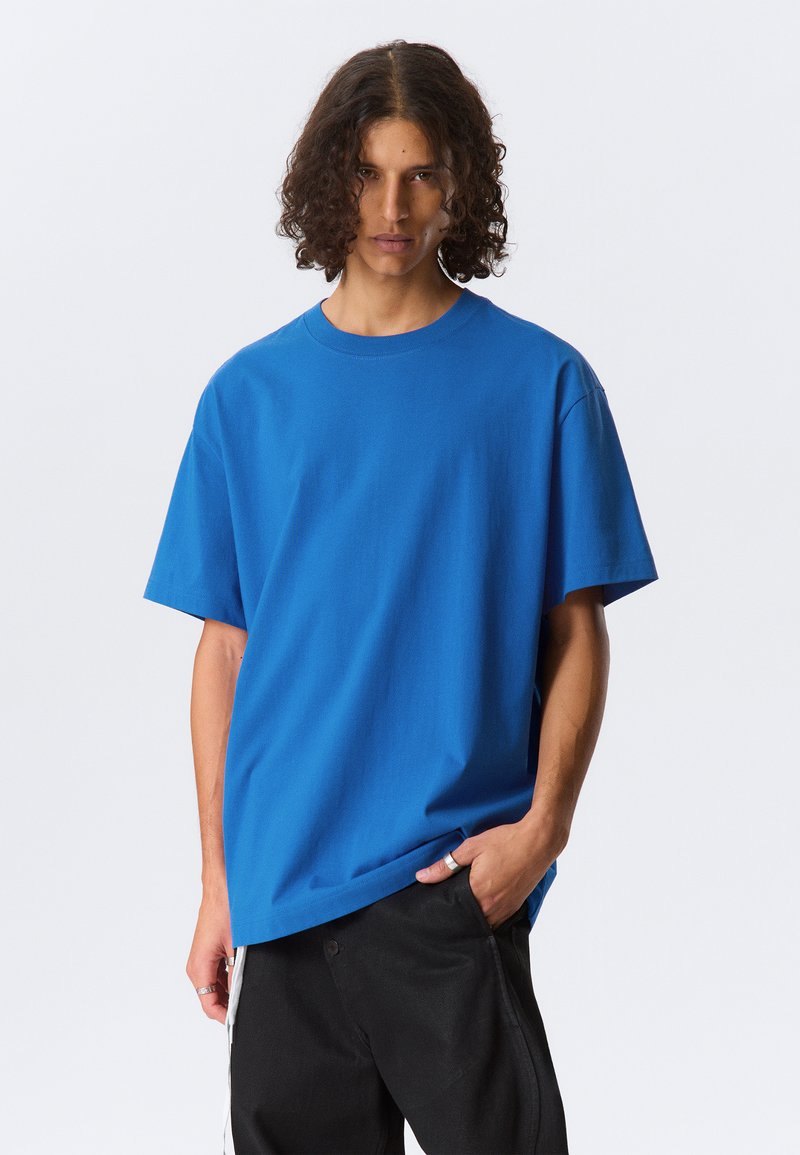 Blue cotton T-shirt with a round neck and short sleeves. The fabric is smooth, featuring a relaxed fit and minimal design details.