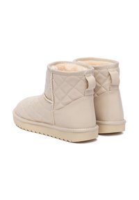 Botas de tobillo acolchadas en color beige con un forro interior suave, suela de goma plana y una lengüeta trasera para ponérselas fácilmente. Adecuadas para un uso casual.
