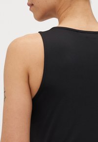 Svart ermeløs tanktop med en glatt, tettsittende tekstur. Har en rund halslinning og rene sømmer langs armhulene.