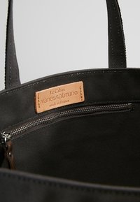Zwarte stoffen tote bag met stevige handvatten, met een leren label waarop staat "Le Cabas vanessasbruno made in France" en een binnenzak met rits.