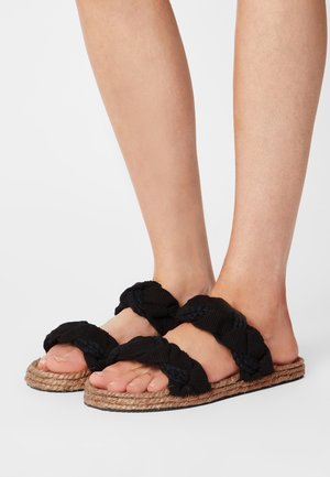 Sandales en tissu tissé noir avec des brides épaisses nouées, dotées d'une semelle en corde naturelle et d'un design plat.