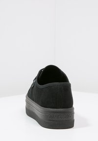 Sneaker in suede nero con punta rotonda, parte superiore texture e suola in gomma nera spessa. Presenta una marcatura minimalista sul tallone.