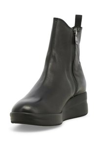 Stivale alla caviglia in pelle nera con un design elegante, chiusura con zip, accentuazione elastica e suola a zeppa per un'altezza extra. Texture liscia con cuciture minime.