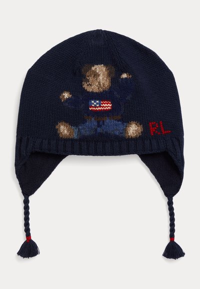 Cappello invernale di lana blu navy con paraorecchie e nappine intrecciate, con un orsetto che indossa un maglione con la bandiera americana e le iniziali rosse "RL".