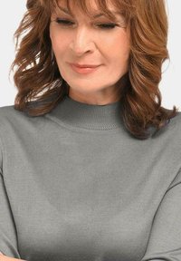 Grauer gerippter Rollkragenpullover mit figurbetontem Design, hochgeschlossenem Kragen und schmalen Ärmeln. Glatte Textur mit dezentem Glanz.