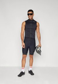 Svart sykkeldrakt med ermeløs topp og knelengde shorts, med glidelås foran. Tilbehør inkluderer hjelm og solbriller.