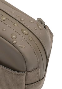 Wasserabweisende beige Schultertasche mit einer glatten, gepolsterten Oberfläche, auf der sichtbare Wassertropfen zu sehen sind, sowie einem strukturierten Seitenpaneel.