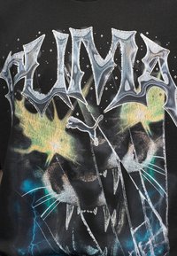 Ένα άγριο πρόσωπο πάνθηρα με λαμπερά μάτια και φανερά δόντια κάτω από το έντονο, κοφτερό κείμενο "PUMA" και το λογότυπο ενός πηδώντας πάνθηρα σε σκοτεινό φόντο.