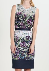 Květinové šaty bez rukávů s výstřihem do V, složitými vzory květin a motýlů, tmavě modrým pruhem v pase a přiléhavým střihem.