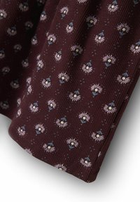 Burgundy tyg med ett texturerat ribbmönster, prydd med små ljusrosa och blå blommor, accentuerade med vita mitten och delikata detaljer.