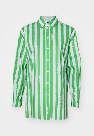 Camicia a righe verdi e bianche con maniche lunghe, chiusura con bottoni sul davanti e un motivo di testo ripetuto con la scritta "sport" in bianco. Materiale in cotone.