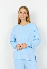 Hele sinine pusa lõdva lõikega, pikkade varrukate ja ümar kaelusega. Omaduseks küljetaskud ja sile, pehme kangas.