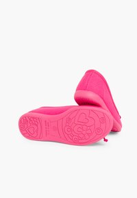 Chaussures en tissu rose avec un bout arrondi, présentant une semelle texturée ornée de motifs floraux et de cœurs, ainsi qu'une languette au talon.