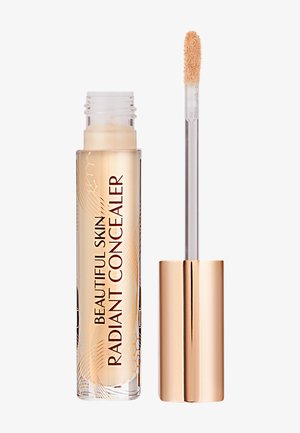 Correcteur dans un tube transparent avec un capuchon doré. Dispose d'un embout applicateur doux et d'un liquide beige clair. Décoré de motifs dorés subtils.