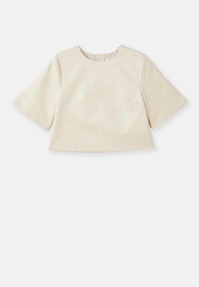 Cremefarvet cropped top lavet af glat materiale, med korte ærmer, rund halsudskæring og subtile syninger.