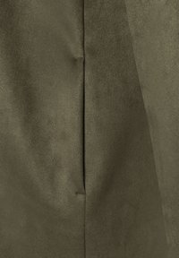 Olivenfarbener Stoff mit einer weichen, suedeähnlichen Textur. Verfügt über eine subtile Naht und einen schwachen Glanz, der die Qualität des Materials hervorhebt.