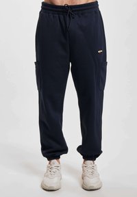 Pantaloni da jogging navy in misto cotone con elastico in vita, tasche laterali, polsini a coste e dettagli testurizzati sui lati.