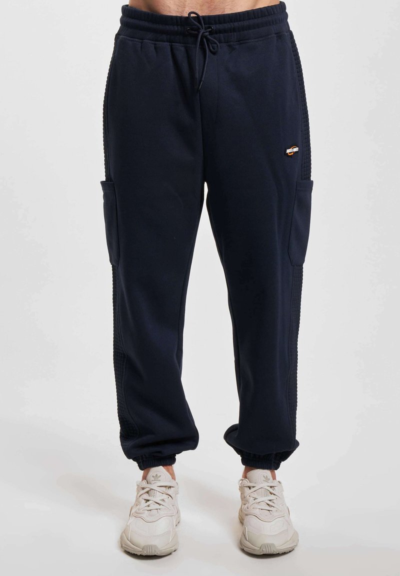 Pantaloni da jogging navy in misto cotone con elastico in vita, tasche laterali, polsini a coste e dettagli testurizzati sui lati.