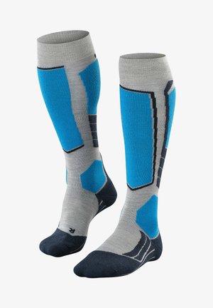 Chaussettes montantes grises avec des accents bleus et noirs. Texture côtelée avec des motifs géométriques et un renfort au niveau des orteils en bleu foncé. Matériau doux.