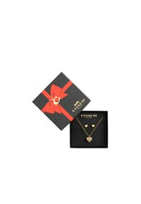 Collier en or avec pendentif en forme de cœur et boucles d'oreilles assorties en forme de cœur, présentés dans une boîte noire avec un ruban rouge et un logo.