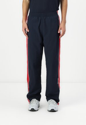 Marineblå track pants med røde sidelæg, elastisk talje og lynlåslommer. Fremstillet af letvægtsmateriale med en afslappet pasform.