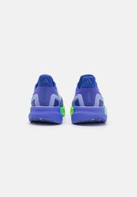 Des baskets de sport violettes avec une tige en maille respirante, une semelle rembourrée en bleu avec des accents en vert néon, et une adhérence texturée sur la semelle.
