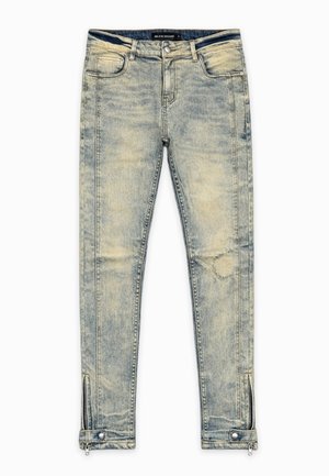 Lichtgewassen skinny jeans met voorzakken, ritssluiting en drukknopdetails bij de enkelboorden, en een vervaagde, versleten textuur over het hele oppervlak.