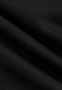 Tejido negro con una textura suave y un patrón acanalado, mostrando pliegues y sombras sutiles, que enfatizan sus cualidades ligeras y elásticas.