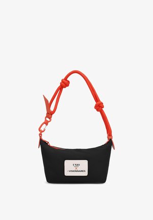Kleine schwarze Handtasche mit leuchtend rotem Kordelgriff und weißem Etikett mit der Aufschrift UNIO x LES VISIONNAIRES auf der Vorderseite.