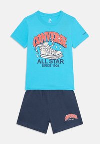 Blå bomulds t-shirt med "CONVERSE ALL STAR" grafik og hvid sneakers design; parret med marineblå shorts med en lille logo detalje.