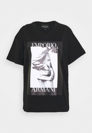 Czarna koszulka Emporio Armani z nadrukiem abstrakcyjnej postaci w odcieniach szarości oraz nazwą marki umieszczoną nad i pod obrazem z przodu.