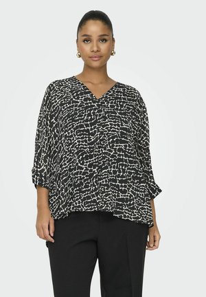 Blouse à motifs noir et blanc avec un col en V, coupe loose et manches trois-quarts. Fabriqué en tissu lisse avec une texture fluide.