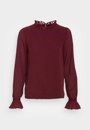 Bordowa bluzka z długim rękawem z teksturowanym wzorem w kropki, z falbankowatym wysokim kołnierzem i rozszerzanymi koronkowymi mankietami.