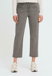 Jeans grises de pierna ancha hechos de una mezcla de algodón con bolsillos delanteros y traseros, asegurados con un botón y una cremallera, combinados con zapatillas beige.