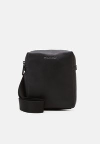 Borsa a tracolla in pelle nera con finitura testurizzata, con logo Calvin Klein; dotata di tracolla regolabile in tessuto e chiusura con cerniera.