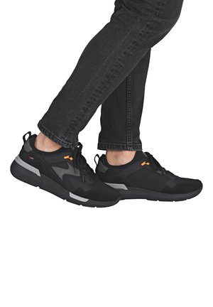 Baskets de sport noires avec une tige en tissu texturé, accents gris et une semelle en caoutchouc. Elles présentent des lacets et une languette à l'arrière.