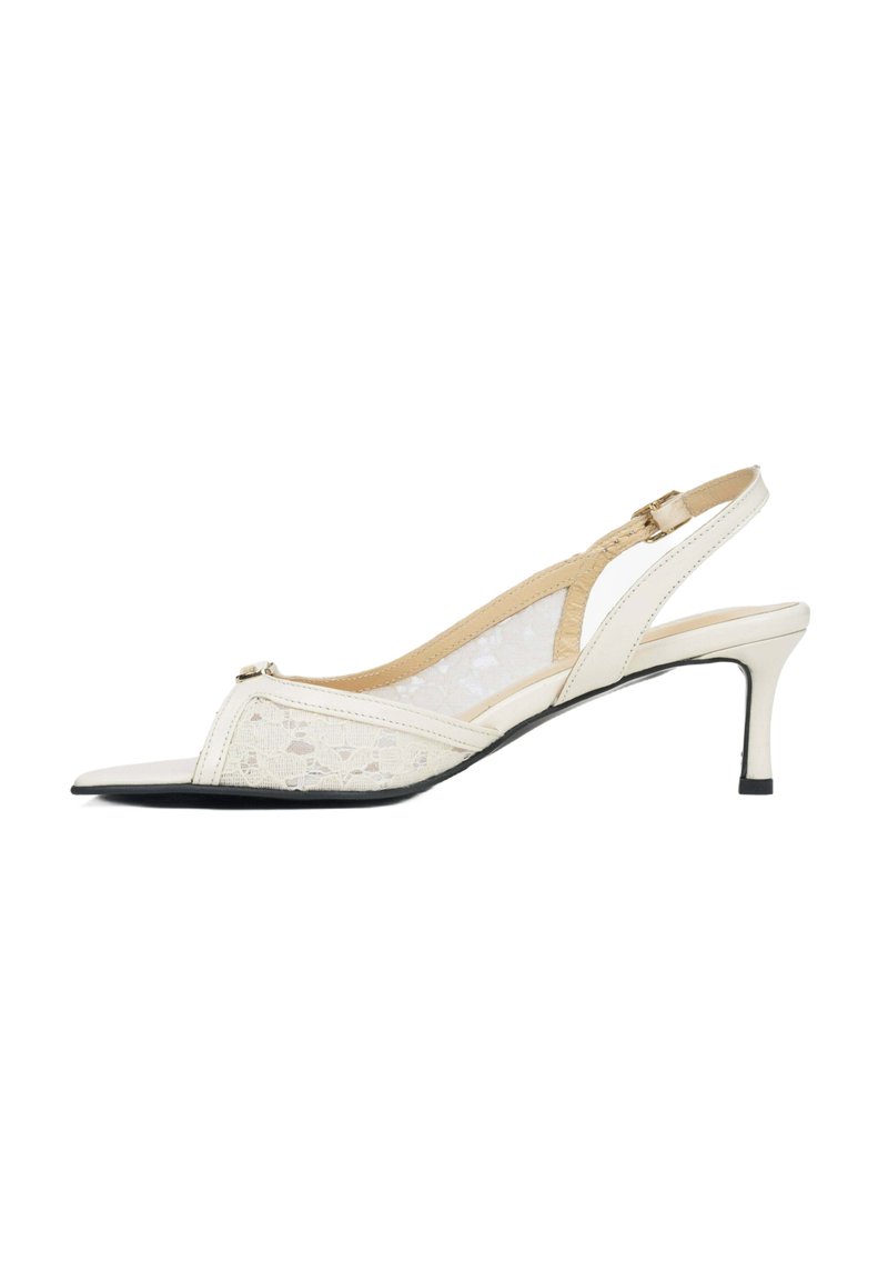 Białe sandały na wysokim obcasie z panelami z koronki, spiczastym noskiem i wąskim obcasem. Posiadają ozdobny akcent blisko noska.