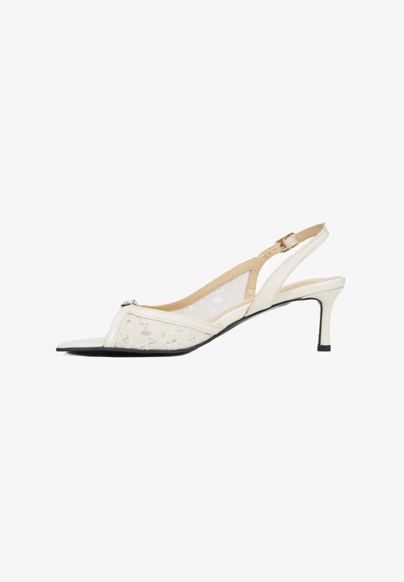 Białe sandały na wysokim obcasie z panelami z koronki, spiczastym noskiem i wąskim obcasem. Posiadają ozdobny akcent blisko noska.