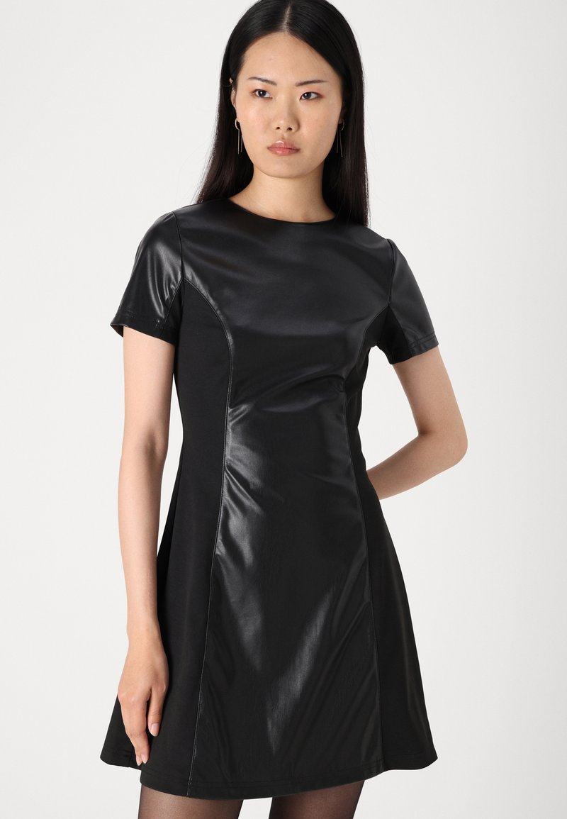 Schwarzes Kleid mit kurzen Ärmeln, das eine Mischung aus matten und glänzenden Texturen aufweist, einen taillierten Oberteil, einen ausgestellt Rock und Nahtdetails hat.