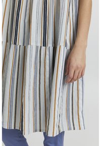 Abito a righe in tessuto leggero con linee verticali in blu navy, arancione e grigio. Strati testurizzati con una forma ampia e fluida.
