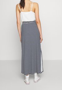 Marinblå och vit randig maxiklänning med sidofrack, i kombination med en vit linne. Har en avslappnad design och elastisk midja.