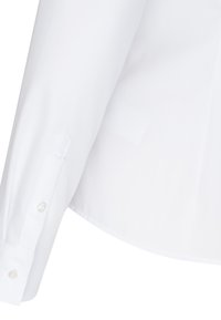 Vit långärmad skjorta med en mjuk textur, knappar vid ärmsluten och en välskräddad design. Har spetsiga ärmslut och klassisk krage.