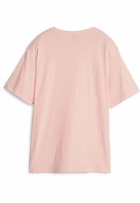 Camisa de algodón rosa claro con un corte holgado, mangas cortas y cuello redondo. Textura suave; sin patrones ni accesorios visibles.