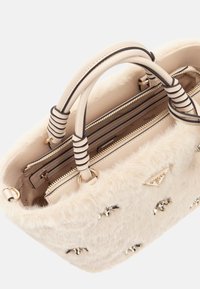 Borsa in pelliccia finta color crema con doppi manici arrotolati, scomparti zip color crema e dettagli decorativi in oro.