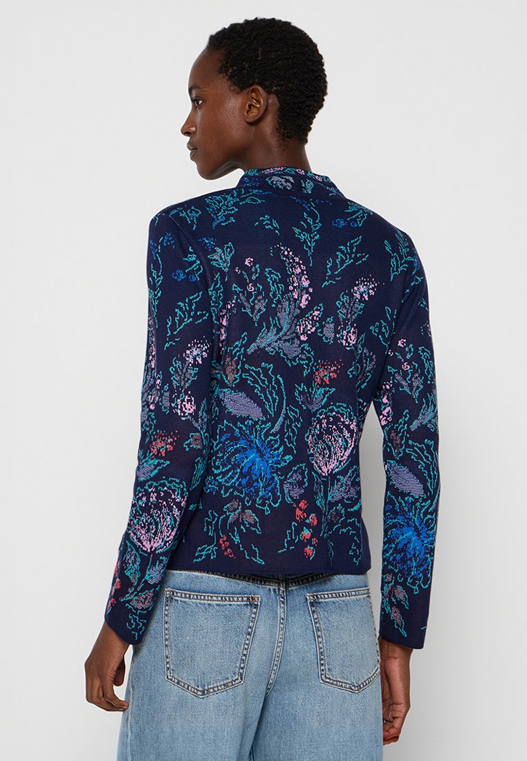 Cardigan bleu marine à motif floral avec manches longues, en tissu tricoté texturé avec des accents rose vif et bleu. Coupe décontractée, encolure ronde.