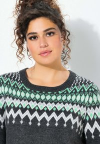 Maglione a maglia con scollatura rotonda, base nera, motivo Fair Isle verde e bianco e texture morbida, adatto per il freddo.