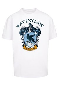 Fehér pamut póló, kék és fekete Ravenclaw címerrel, amelyen egy holló és díszítő elemek találhatók, valamint a "RAVENCLAW" felirat a címer felett.