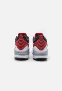 Baskets blanches avec des accents rouges et noirs, dotées d'un talon texturé et d'un logo distinct à l'arrière. Semelle en caoutchouc et col rembourré.